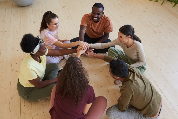Diverse group of people joining hands together in unity and support